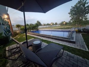 a table and chairs under an umbrella next to a swimming pool at D'Jongke Village in Beran-kidul +9 photos