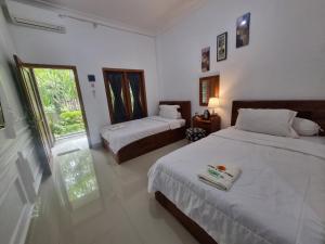 a bedroom with two beds and a window at D'Jongke Village in Beran-kidul