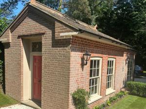 a small red brick building with a red door at The Gatehouse in Trimingham