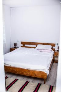 a bedroom with a wooden bed with white sheets at Pensiunea Mateș in Horea +1 photo