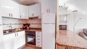 a kitchen with white cabinets and a white refrigerator at La Orilla in San Agustin