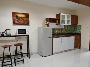 a kitchen with a refrigerator and a table and stools at Phratamnak Grand Apartments - Cozy Beach in Pattaya South
