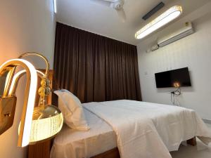 a bedroom with a white bed and a television at Sooru The Beach Stay in Padubidri