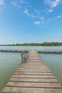 a wooden pier with a bench on the water at Gátőrház Szigetbecse Horgásztanya in Szigetbecse