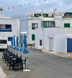 a row of tables and chairs with blue umbrellas at Apartamento Brisa Mar in Famara
