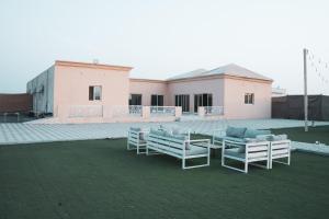 un grupo de sillas y mesas en un césped en New Farmstay Football Kids Pool Zoo, en Adh Dhayd