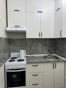 a kitchen with a stove and white cabinets at 1 комнатная квартира видом на горы in Almaty