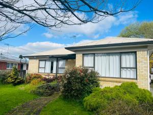 a brick house with white curtains in a yard at Cosy 3 Bedrooms House Beside City Centre in Hamilton