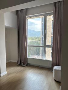 an empty room with a large window with a view at Квартира in Almaty
