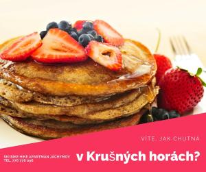 a stack of pancakes with strawberries and blueberries on a plate at Ski Bike Hike Apartment in Jáchymov