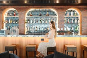 a woman sitting at a bar at Four Points by Sheraton Bangkok Ploenchit Sukhumvit in Bangkok