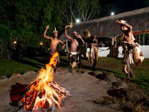 a group of men jumping around a fire at ANEW Hotel Hluhluwe in Hluhluwe