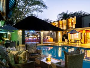 赫卢赫卢韦ANEW Hotel Hluhluwe的一个带椅子的游泳池和一个酒吧的度假胜地