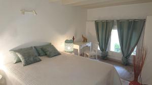 a bedroom with a white bed with green pillows and a window at Les Flamants in Portiragnes +24 photos