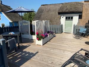 a patio with a table and flowers and an umbrella at Ferienwohnung de lütte Leive in Born in Born +6 photos