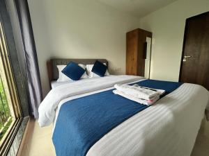 a bedroom with a large bed with blue and white sheets at Zenith Service Apartments - Entire 2BHK Near Mumbai Airport and IIT Powai in Mumbai