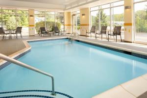 a swimming pool with chairs and tables in a building at Fairfield Inn & Suites by Marriott Towanda Wysox in Towanda