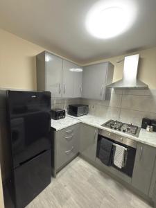 a kitchen with a black refrigerator and gray cabinets at Luxury 2-Bedroom Home 10 Minutes from Birmingham City Centre in Birmingham +12 photos