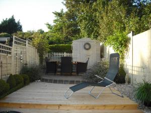 a chair sitting on a wooden deck in a garden at Charmantes Cottage im Landhausstil in Kearsney, Dover 