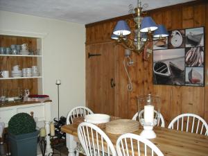 a dining room with a wooden table and white chairs at Charmantes Cottage im Landhausstil in Kearsney, Dover 