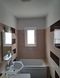 een badkamer met een bad, een wastafel en een raam bij LCB Apartments Braşov in Braşov