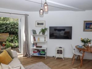 a white living room with a table and a tv at The Workshop in Tavistock