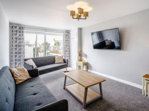 a living room with a couch and a table at Gwbert Holiday Cottages, Riversmouth in Gwbert
