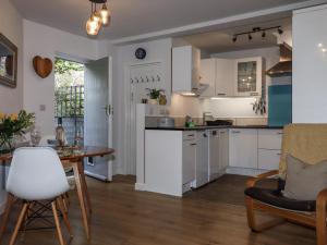 a kitchen with white cabinets and a table and chairs at The Workshop in Tavistock