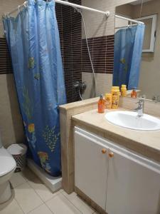 a bathroom with a sink and a blue shower curtain at Locationsecurity in Tunis