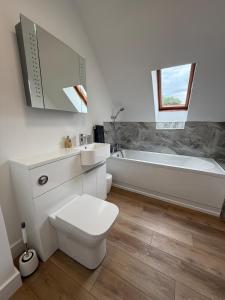 a bathroom with a toilet and a tub and a sink at Highland Nook for 4 in Fort William