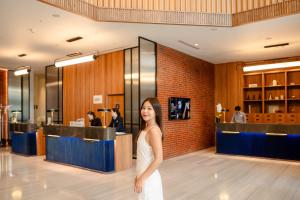 a woman in a white dress standing in a lobby at Four Points by Sheraton Bangkok Ploenchit Sukhumvit in Bangkok