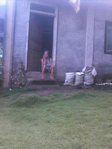 a woman sitting on the porch of a house at Belmoro Transient House in Bacacay +2 photos