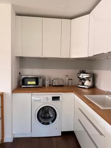 Una cocina con gabinetes blancos y lavadora. en Home Parc by So Homy - 3 Bed Room, 6 People, en Saint-Ouen