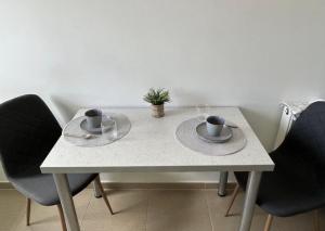 a white table with two cups and plates on it at LCB Apartments Braşov Avantgarden 3 in Braşov