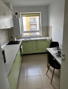 a kitchen with green cabinets and a table and a window at LCB Apartments Braşov Avantgarden 3 in Braşov