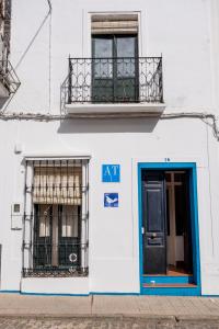 ein weißes Gebäude mit einer blauen Tür und einem Balkon in der Unterkunft Alojamiento "Casa Paloma" in Villanueva del Fresno