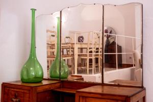 zwei grüne Vasen auf einem Tisch mit einem Spiegel in der Unterkunft Alojamiento "Casa Paloma" in Villanueva del Fresno