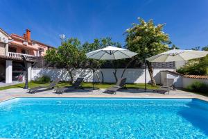 - une piscine avec deux parasols et des chaises à côté dans l'établissement Stone House Furlani, à Svetvinčenat
