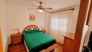 1 dormitorio con cama verde y ventilador de techo en Port Beach I Puerto Sagunto en playa cerca de Valencia, en Puerto Sagunto