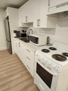 a white kitchen with a stove and a microwave at Peace Abode in Dieppe