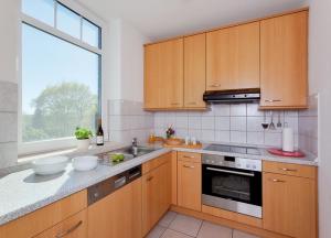 ツィノヴィッツにあるFerienwohnung Haus Roland Whg 26の木製のキャビネットとシンクと窓のあるキッチン