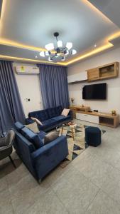 sala de estar con 2 sofás azules y TV de pantalla plana en Home of comfort and luxury, en Apenkwa