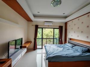 a bedroom with a bed and a tv and a window at Phratamnak Grand Apartments - Cozy Beach in Pattaya South