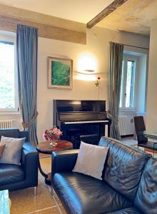 a living room with a leather couch and a piano at Vatican Prestige - Meospiti Cesare Exclusive in Rome