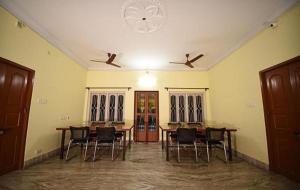 a room with a table and chairs and a ceiling fan at FabHotel Sonar Bangla Guest House in Kolkata