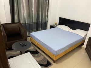 a bedroom with a bed and a chair and a table at Appartement Sewa ACI 2000 in Bamako