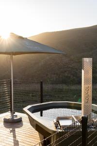 a hot tub on a deck with an umbrella at Nicara Luxury Ecocabin Honeypunch 