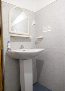 a bathroom with a white sink and a mirror at The Hollyoak - Vintage Charm with Modern Comforts in Denipitiya