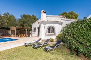 un groupe de chaises assises dans l'herbe au bord d'une piscine dans l'établissement Casa Isabela, à Jávea
