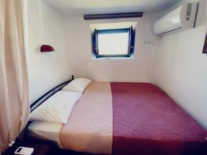 a small bedroom with a bed and a window at ANCIENT MEROPIA - ARTEMIS, Traditional House- Family, Apollonia in Apollonia